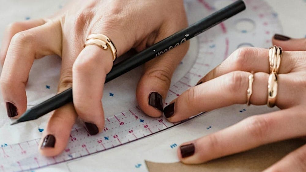 Pair of hands measuring pattern with ruler and pencil