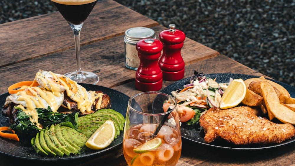 Image of 2 meals on outdoor table, with condiments and drinks
