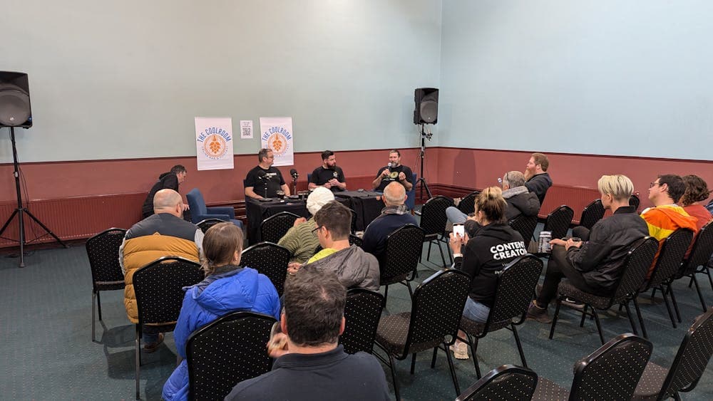 Panel of brewers in front of a seated crowd listening