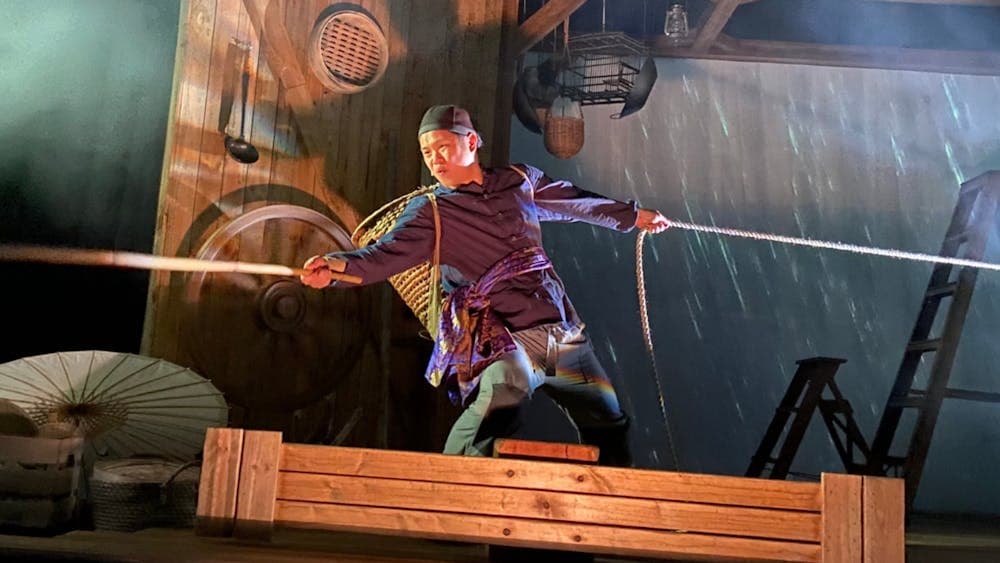 A young man straining, trying to hold on to two ropes