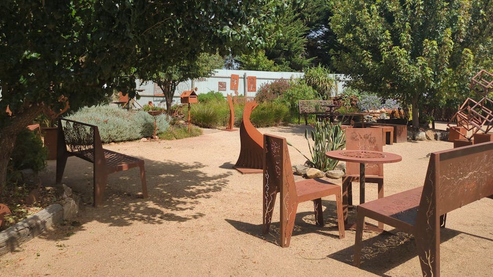 Metal garden seats and benches around a table in the garden.