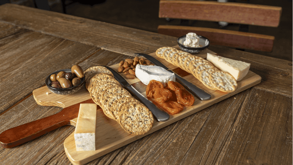 A wooden board with cheeses, biscuits, dried fruits and nuts