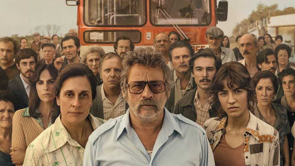 a large group of people facing the camera with a bus behind them