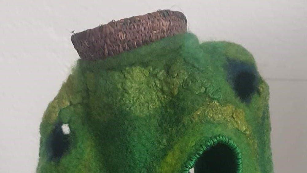 A sculpture made of green dyed felt with holes in it