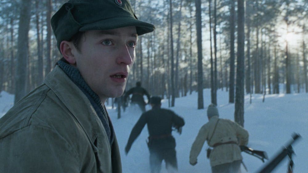 Man stands in snowy forest as others run into distance