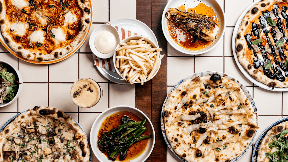 Pizzas and sides served on plates and placed on a table