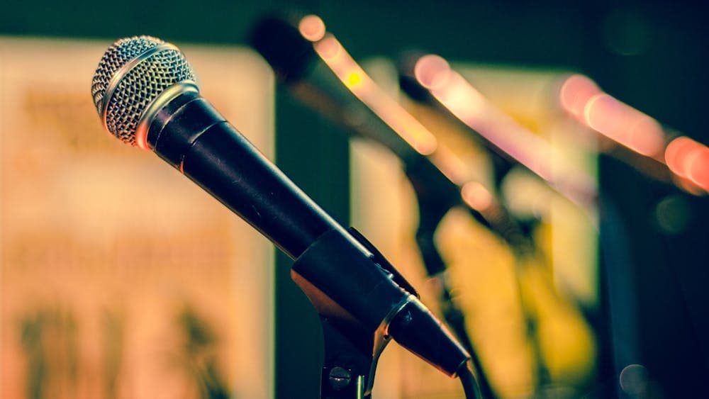 A row of microphones on a stage under lights