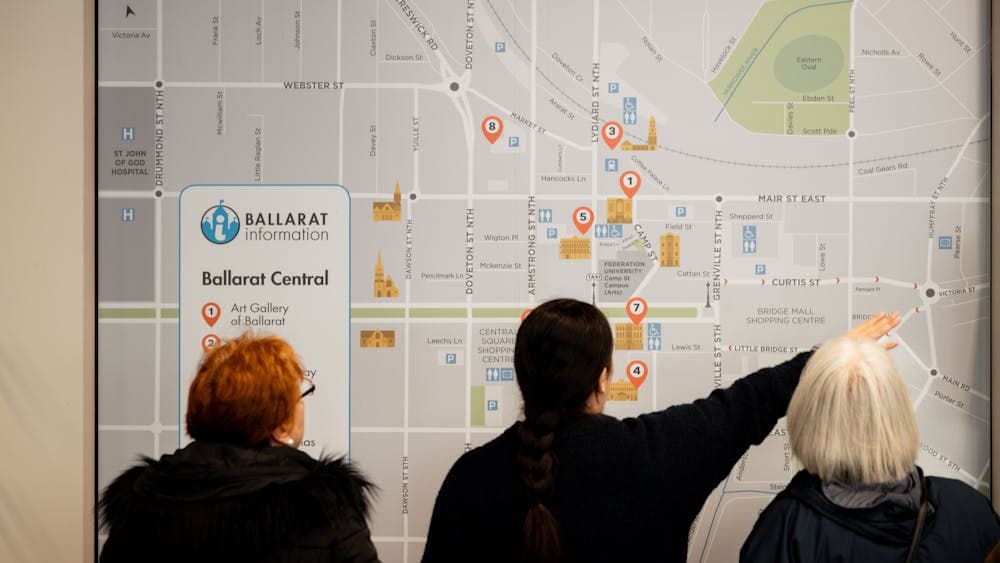 Sophia shows 2 visitors where to go on a large scale map on the wall