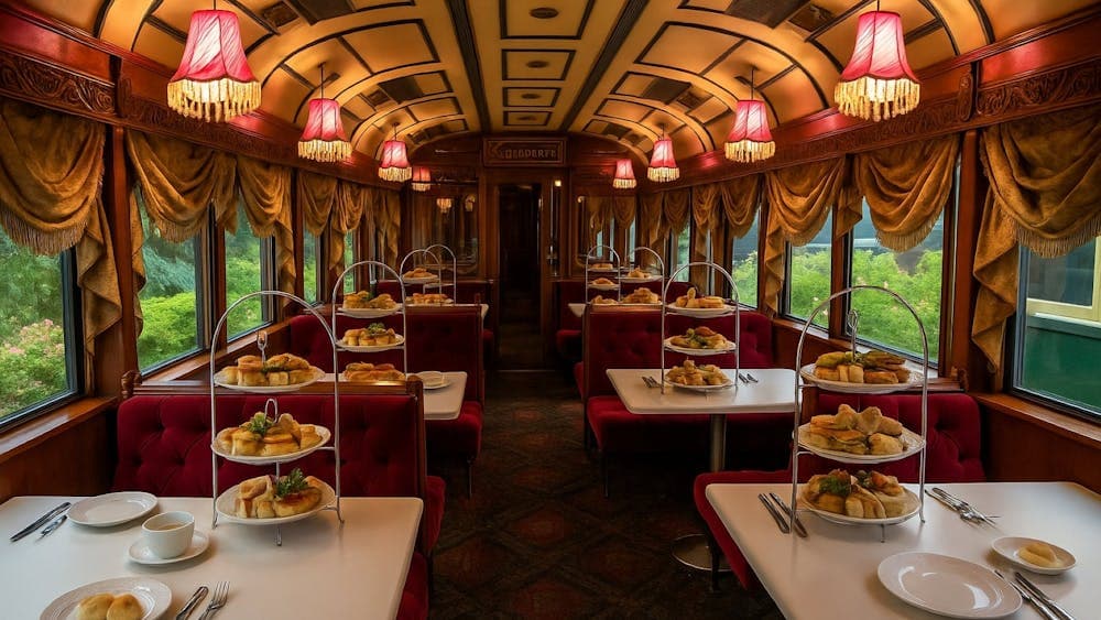 interior of a vintage train cart with red sofa booths and tables with tea pots, cups and a stand