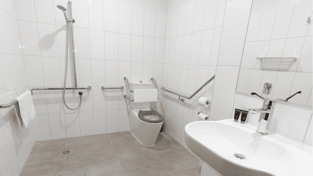 Accessible bathroom with shower, toilet rails, and sink designed for mobility access.