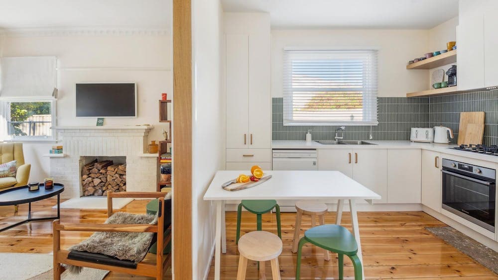 Kitchen table, stools, sink and part of loungeroom with TV