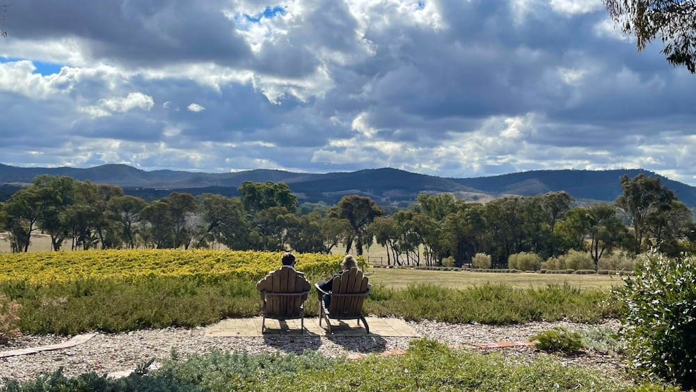 A couple seated outdoors at Bigibila Wines taking in the stunning views on a Silver Mink Tour