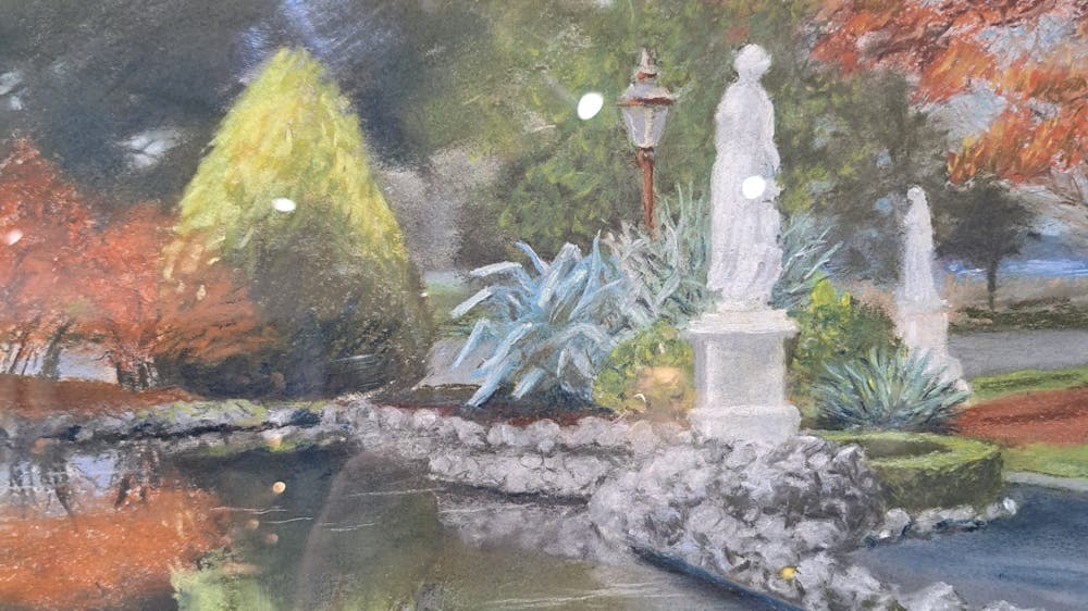 Reflections of statues and garden in the stone lined pond at Autumn