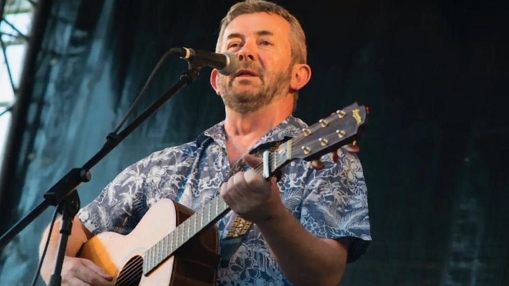 A man holding a guitar singing into a microphone