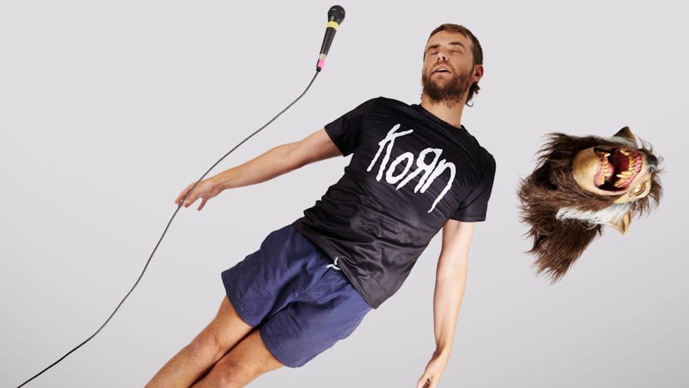 A guy floating through the air with a microphone and werewolf mask