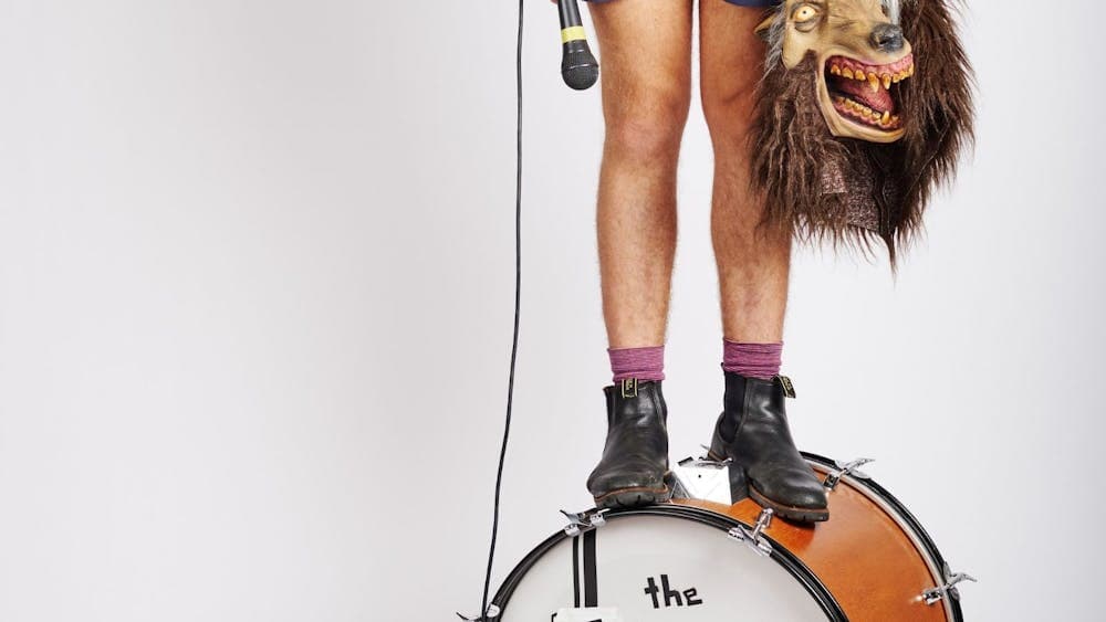 Guy standing on a kick drum with 'The Teeth' written on it in black tape.