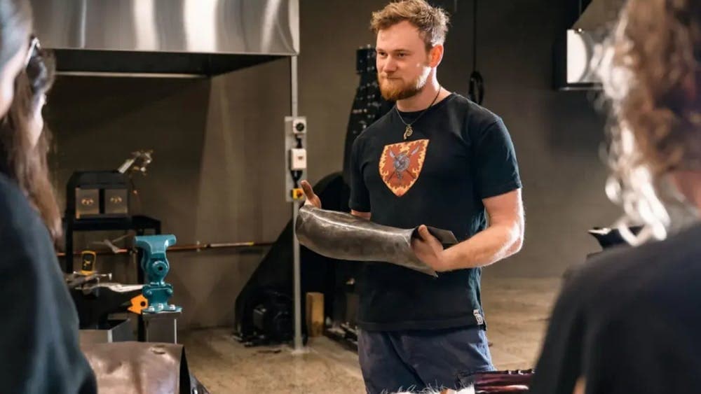 Rob Hayes holding up a metal vambrace in a workshop