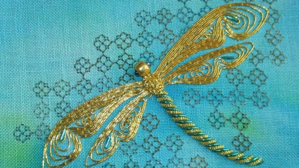 Gold embroidered dragonfly on blue fabric