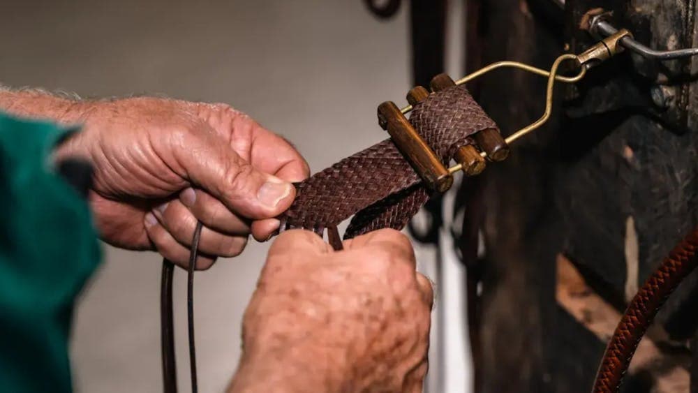 Close up of a pair of hands plating a leather belt