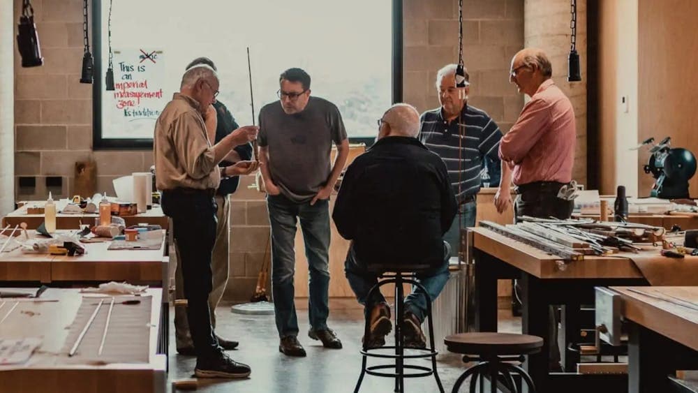 Five men inside a cane rod workshop talking