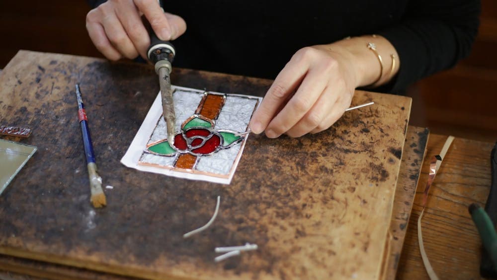 Hands cutting and constructing glass with floral design