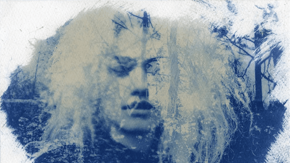 Blue and white cyanotype portrait of a person with shoulder-length white hair
