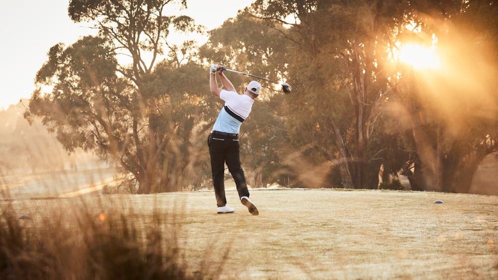 Man mid-swing on golf course