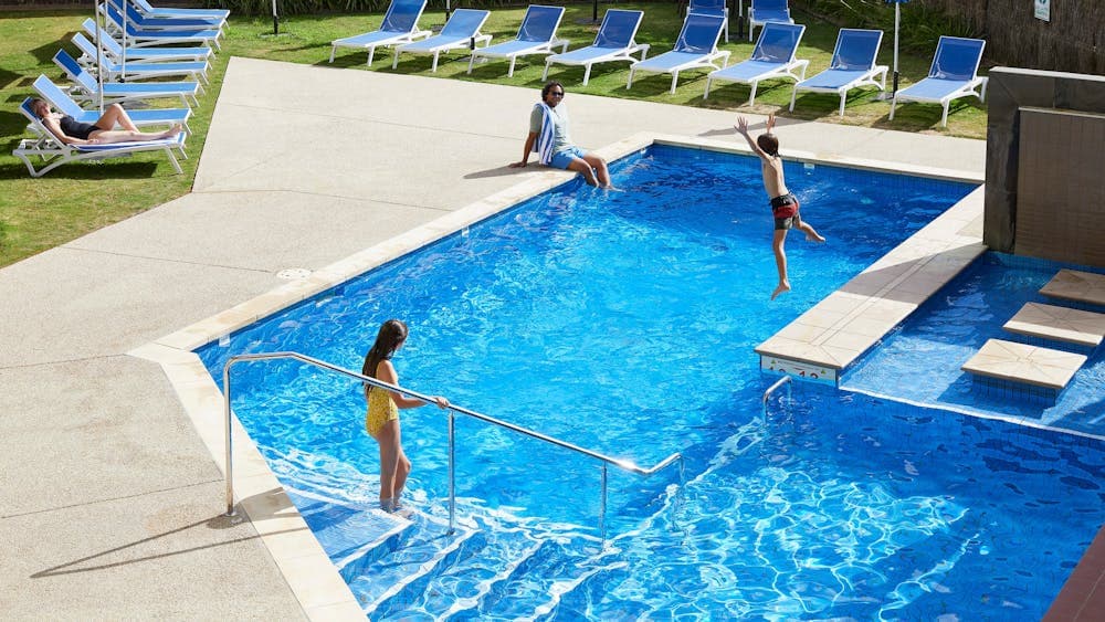 Family swimming and lounging by pool