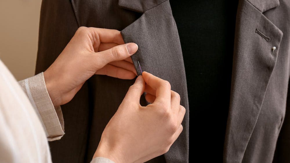 Pair of hands pinning jacket collar