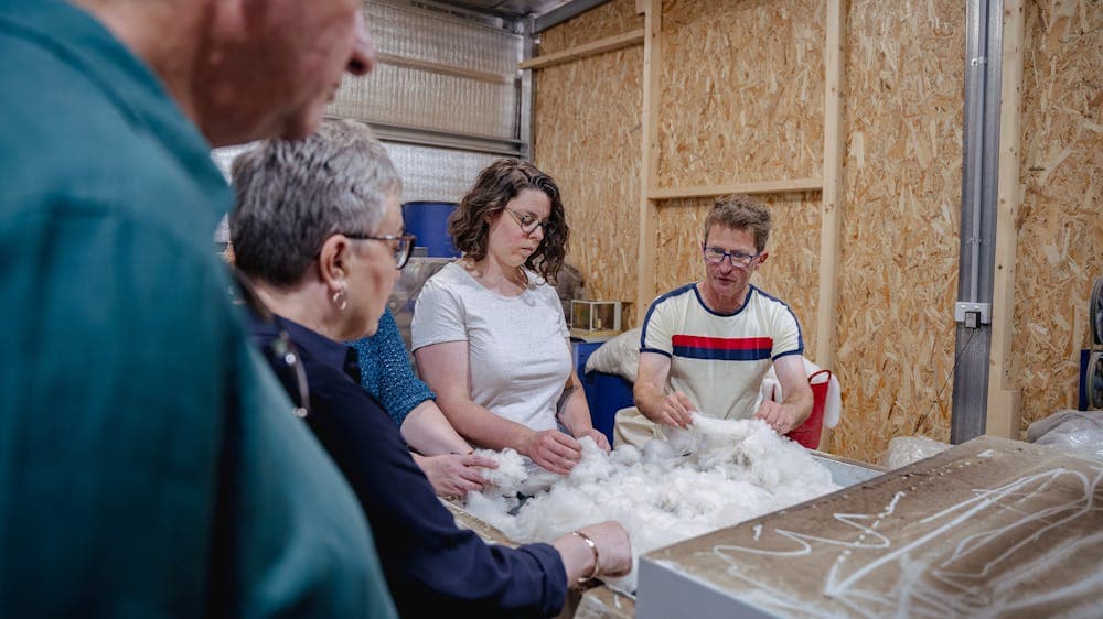 4 people at the carder filling it up with fibre