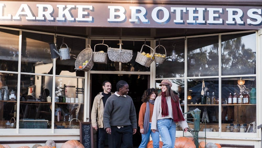 Two men and two women walking out of Clarke Bros Grocers store