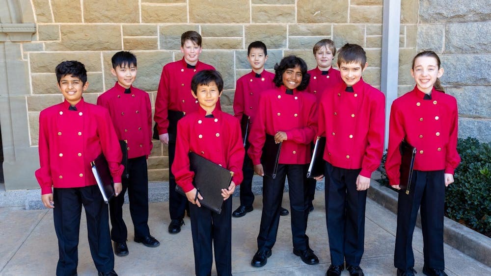 9 members of the Australian Boys Choir stand together holding their music folders