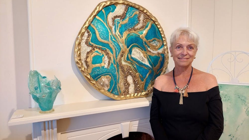 Resin artist Beatrice is pictured with pieces of her artwork in her favorite color, turquoise.