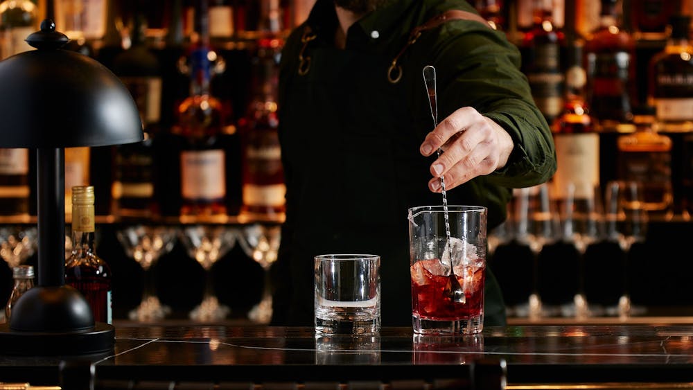 Bartender making cocktail behind bar