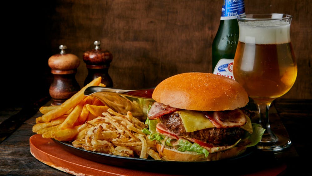 Wagyu Beef Burger with a bottle and glass of beer and salt and pepper shakers in the background