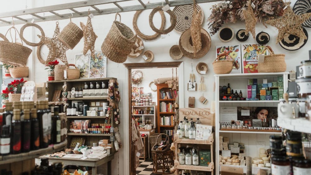 A shop full of many wares, including baskets hanging from celling, and shelves full  of products.