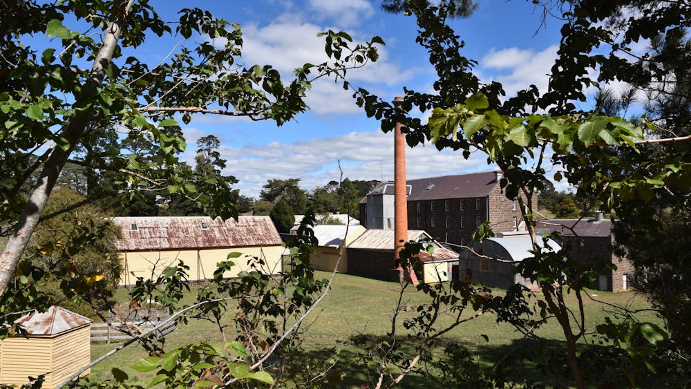 This photo show the bluestone mill, the large weatherboard granary and the tall red brick chimney