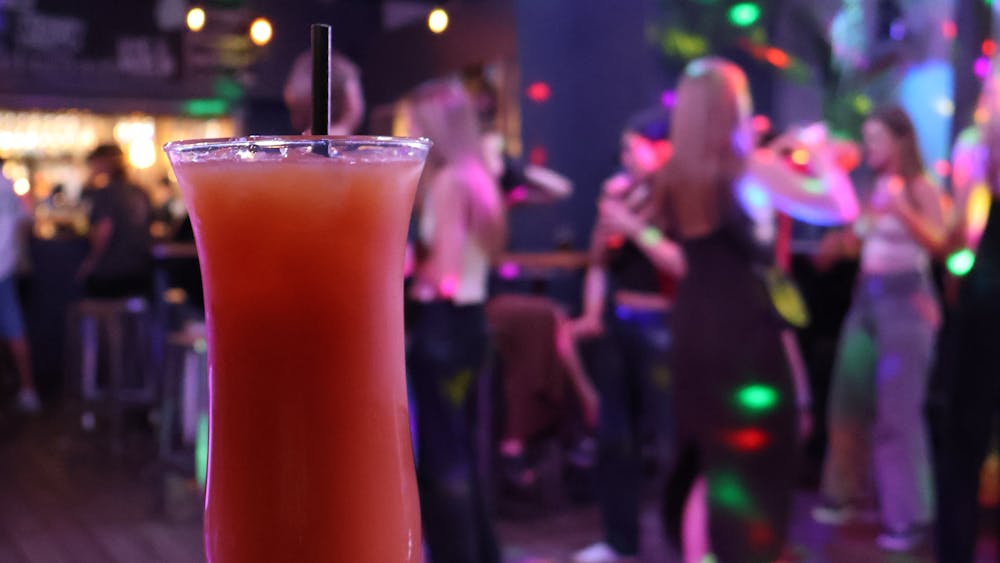 Cocktail on a table with guests dancing in the background at Freight Bar.