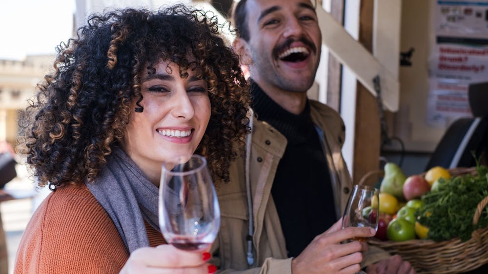 Woman holding up a glass wine smiling to camera