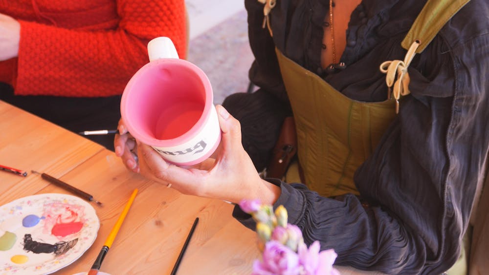 A close up of a person painting a mug red