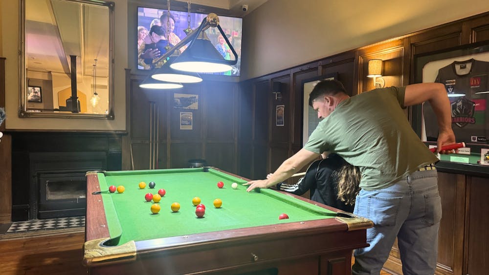 Two people playing pool on a billiards table inside the Courthouse Hotel bar.