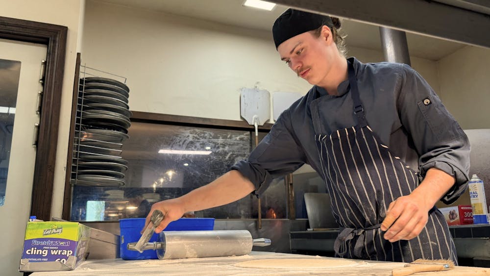 A chef working in the Courthouse Hotel kitchen preparing food on a wooden bench.