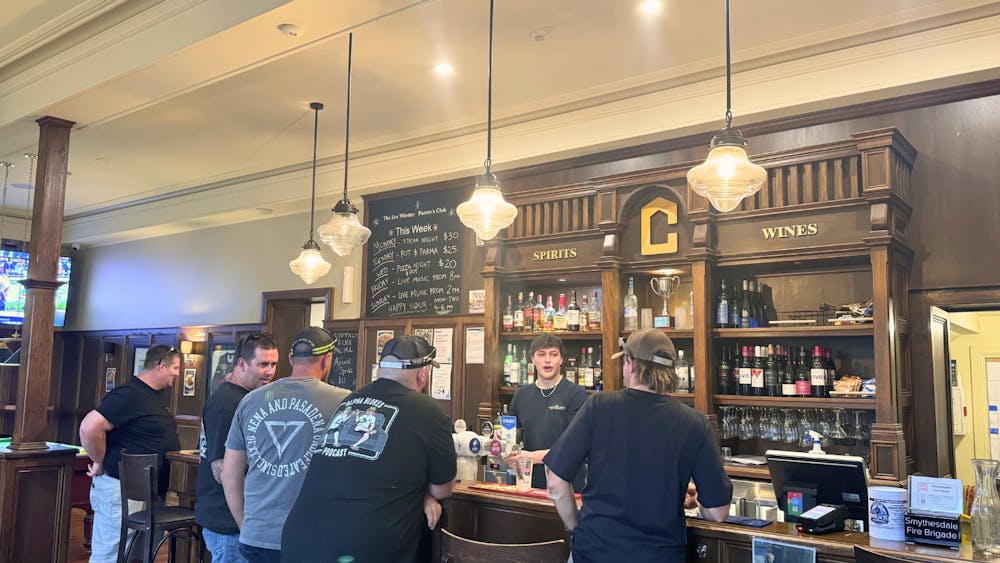 Patrons standing at the bar ordering drinks inside the Courthouse Hotel.