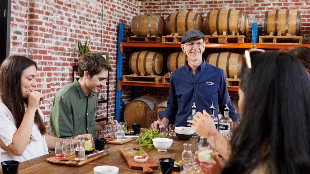 A group if people sitting around a table with a variety of spirits available for tasting