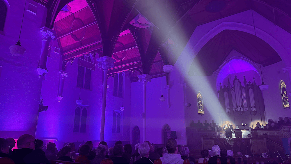A chapel interior with purple lighting and a performer in a spotlight