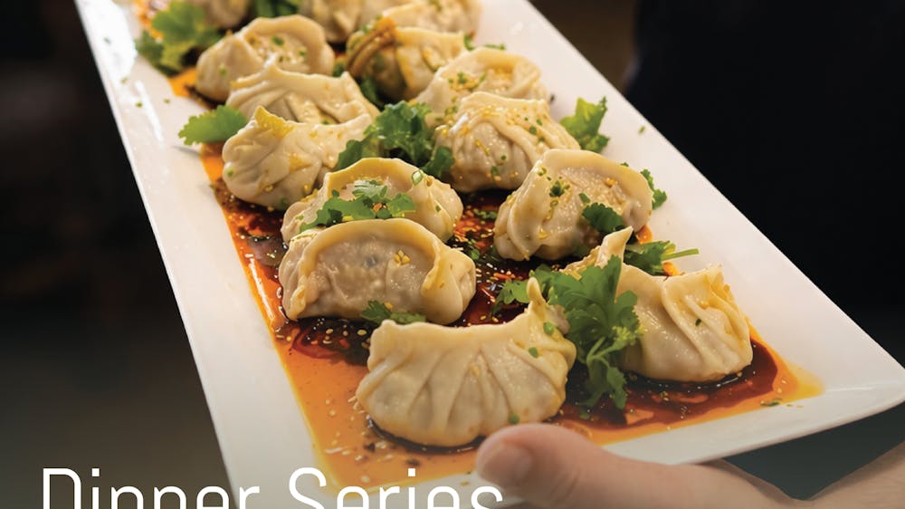 A platter of dumplings with sauce and coriander leaves scattered