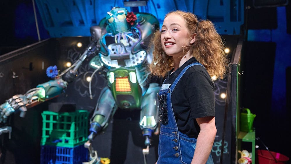Juniper (Adeline Hunter) in front of her singing robot friend