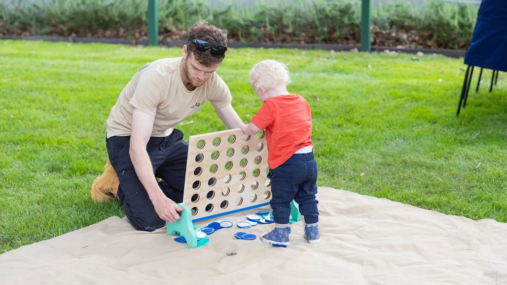 A toddler plays connect 4 with his father.
