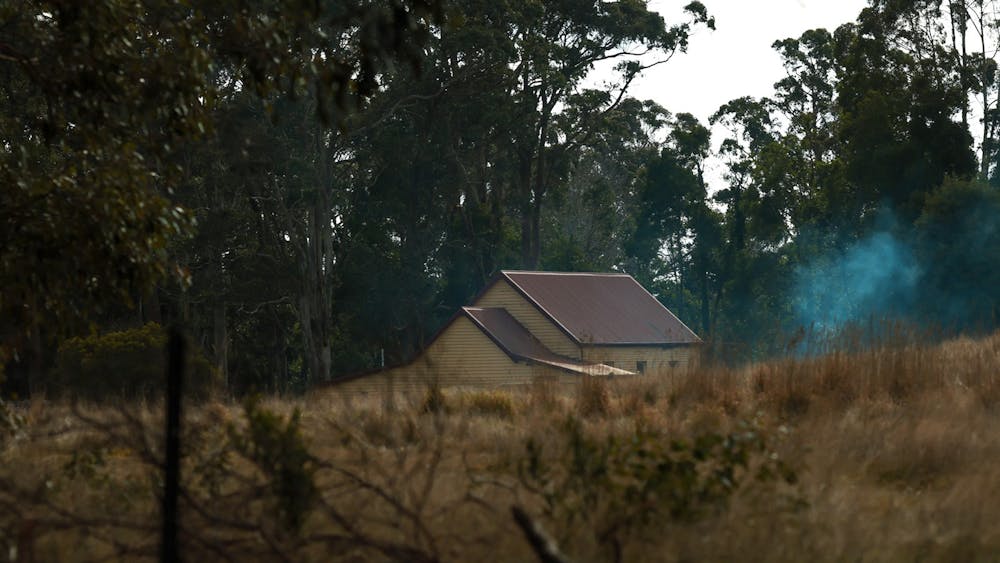 a house in the distance surrounded by trees and grass