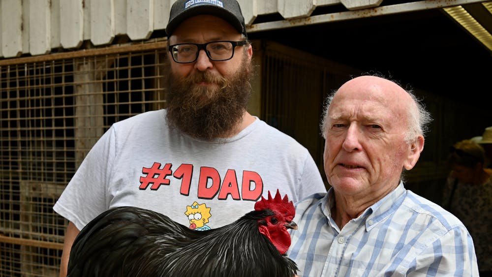 2 men with one holding big black chichen